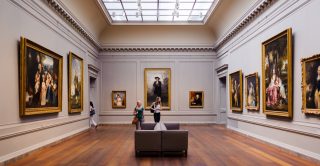 Two women walk through an art gallery