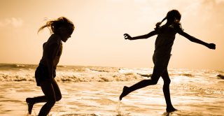 Children play in the sea silohuetted by the sun