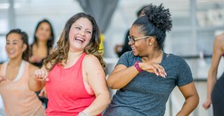 Two middle aged women enjoy an exercise class