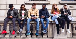 Teenagers sit along a wall