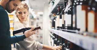 Couple choose wine from supermarket shelf