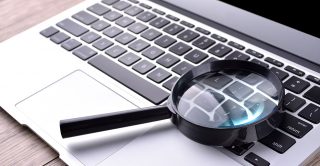 Magnifying glass placed on a laptop keyboard